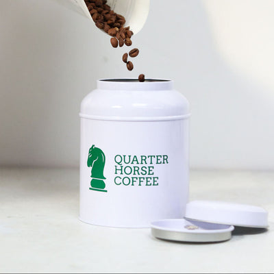Person pouring coffee beans into a 'Quarter Horse Coffee' container.